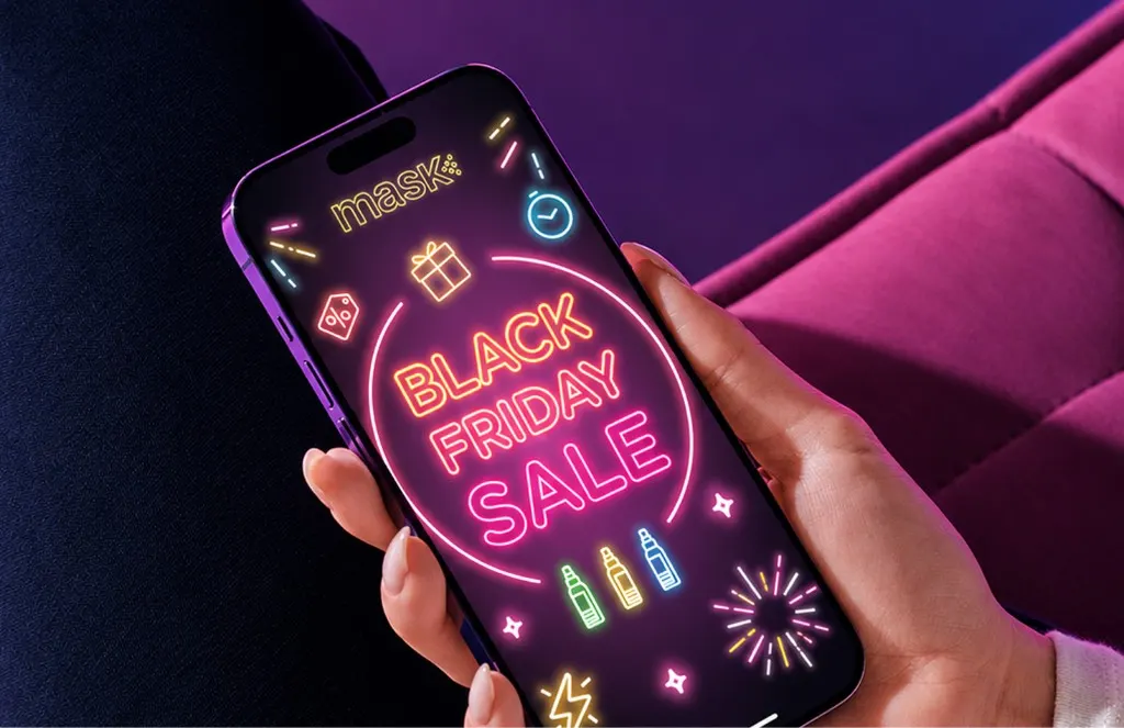 Hand holding a phone with a glowing neon MaskCo Black Friday sale graphic, against a pink seat
