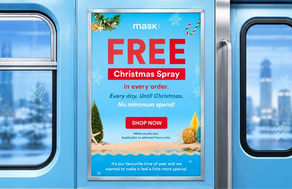 Poster on a train door between two windows, offering a free MaskCo Christmas spray in every order