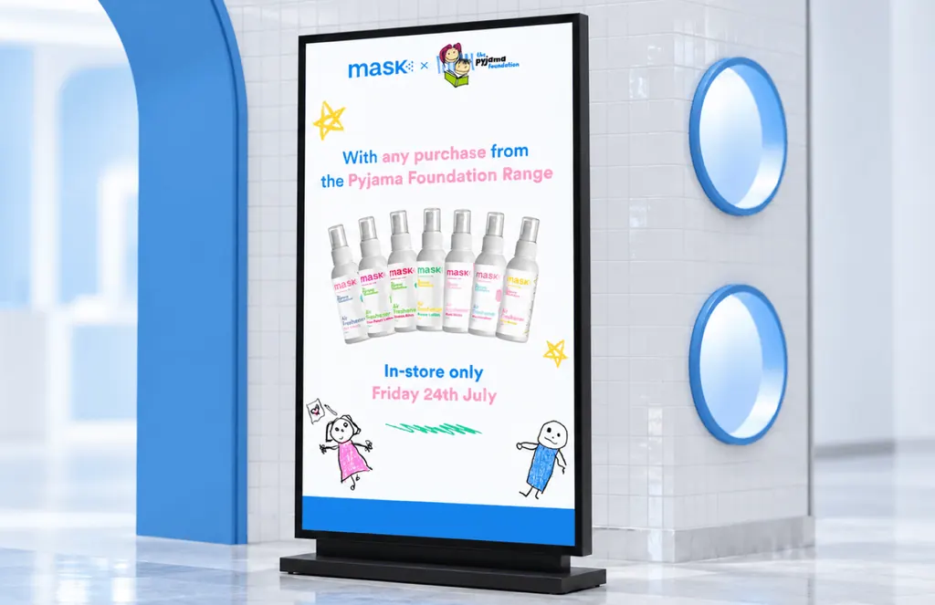Free-standing MaskCo x Pyjama Foundation sign in a white store, with a row of sprays and crayon-style drawings