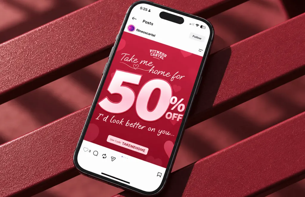 Phone on a red bench showing a Fitness Cartel Instagram post: Take me home for 50% off, with code TAKEMEHOME